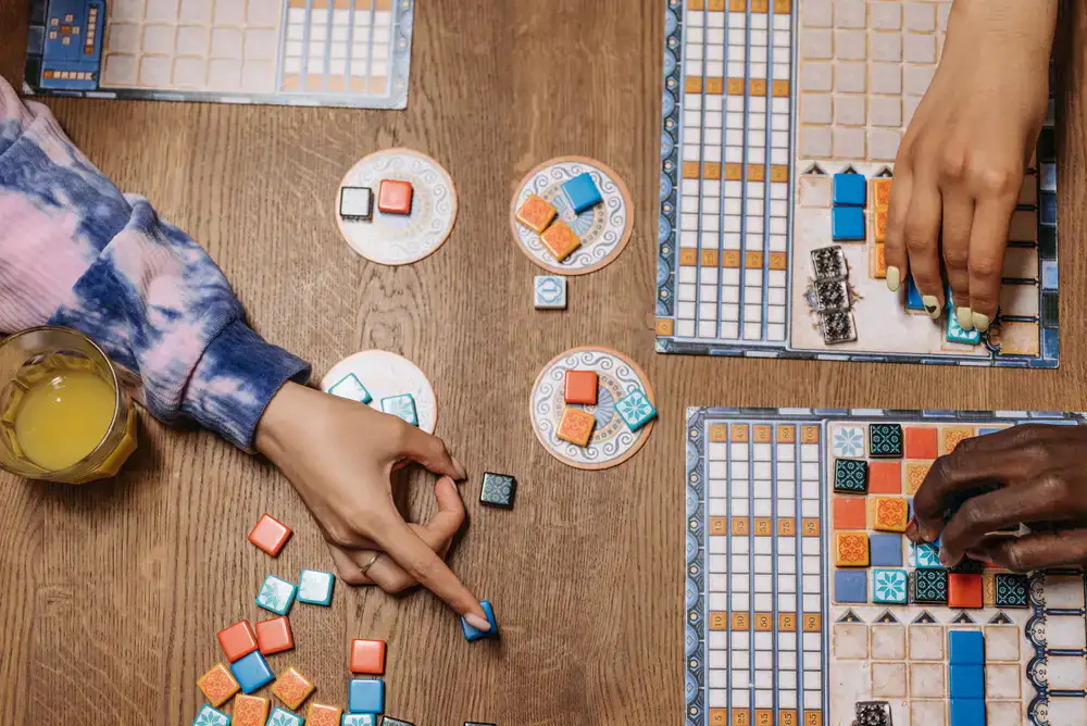 People playing a strategy board game at a large wooden table